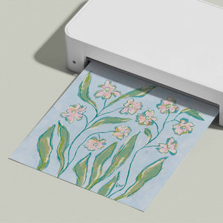 A white printer is shown in the image, with a printed paper featuring a floral design of pink flowers and green leaves.