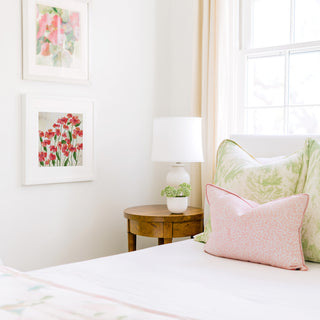 a cozy bedroom corner with a bed, a wooden nightstand, and a framed artwork on the wall.