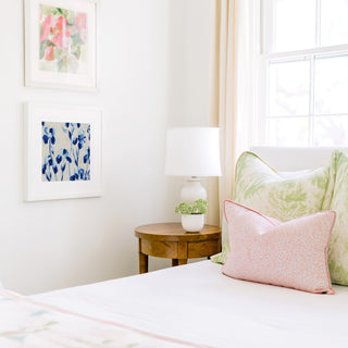 a cozy bedroom corner with a bed, a wooden nightstand, and a framed artwork on the wall.