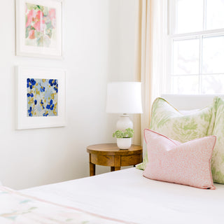 a cozy bedroom corner with a bed, a wooden nightstand, and a framed artwork on the wall.