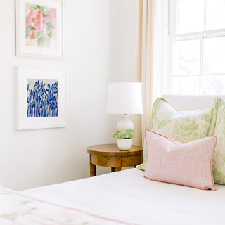 a cozy bedroom corner with a bed, a wooden nightstand, and a framed artwork on the wall.