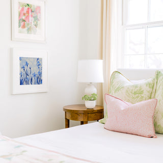 a cozy bedroom corner with a bed, a wooden nightstand, and a framed artwork on the wall.
