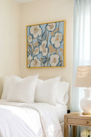 a serene and well-decorated bedroom with a large floral painting hanging on the wall above a bed with white bedding and pillows.