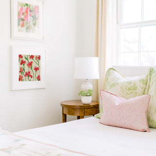 a cozy bedroom corner with a bed, a wooden nightstand, and a framed floral artwork on the wall.