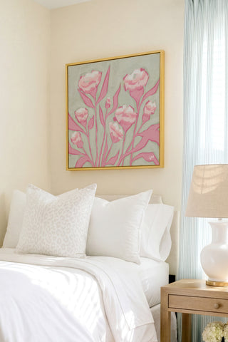 a bedroom with a bed, a nightstand, and a framed artwork of pink flowers hanging on the wall above the bed.