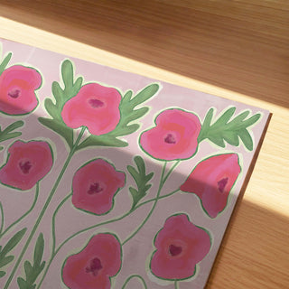 a close-up view of a painting or artwork depicting a pattern of pink flowers with green leaves.