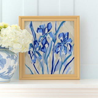 a framed painting of blue flowers on a white shelf, with a vase of white hydrangeas placed next to it.