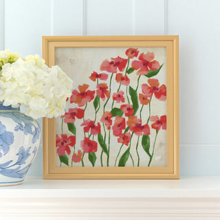 a framed painting of red flowers on a white background, placed on a shelf next to a blue and white vase with white flowers.