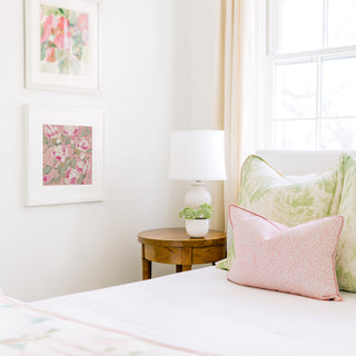 a cozy bedroom corner with a bed, a wooden nightstand, and a framed floral artwork on the wall.