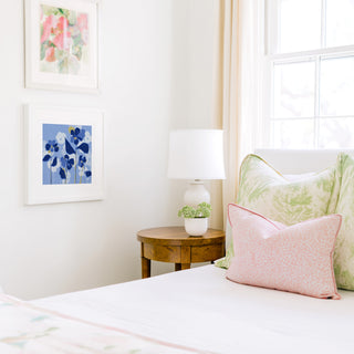 a cozy bedroom corner with a bed, a wooden nightstand, and a framed artwork on the wall.
