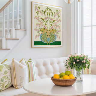 a cozy living room with a white sofa, a round table with a basket of fruit, and a framed painting of a floral arrangement hanging on the wall.